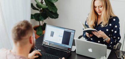 Professional coworkers collaborating in a modern office setting with laptops and a notebook.