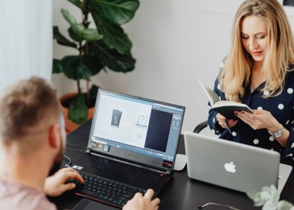 Professional coworkers collaborating in a modern office setting with laptops and a notebook.